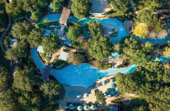 an aerial view of a pool surrounded by trees