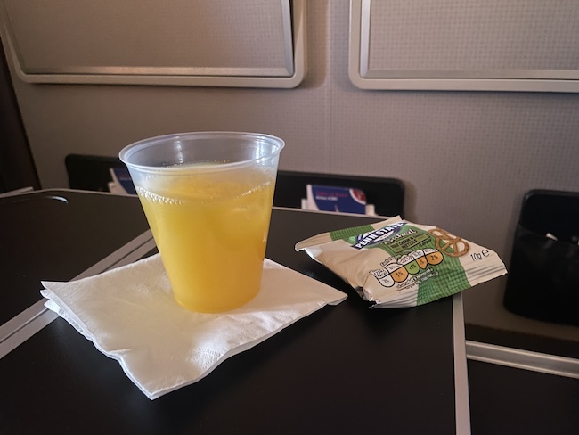 a cup of orange liquid and a bag of food on a table