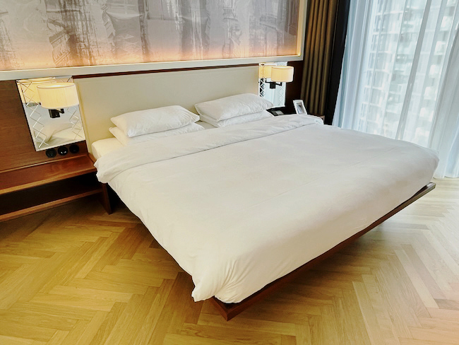 a bed with white sheets and lamps
