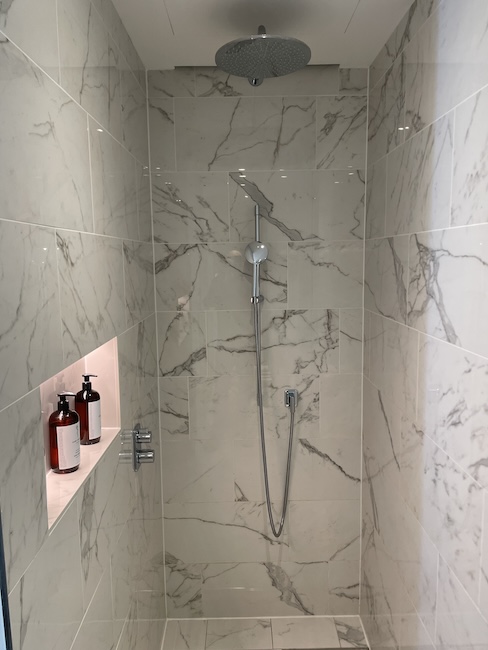 a shower with a shower head and a shelf with bottles